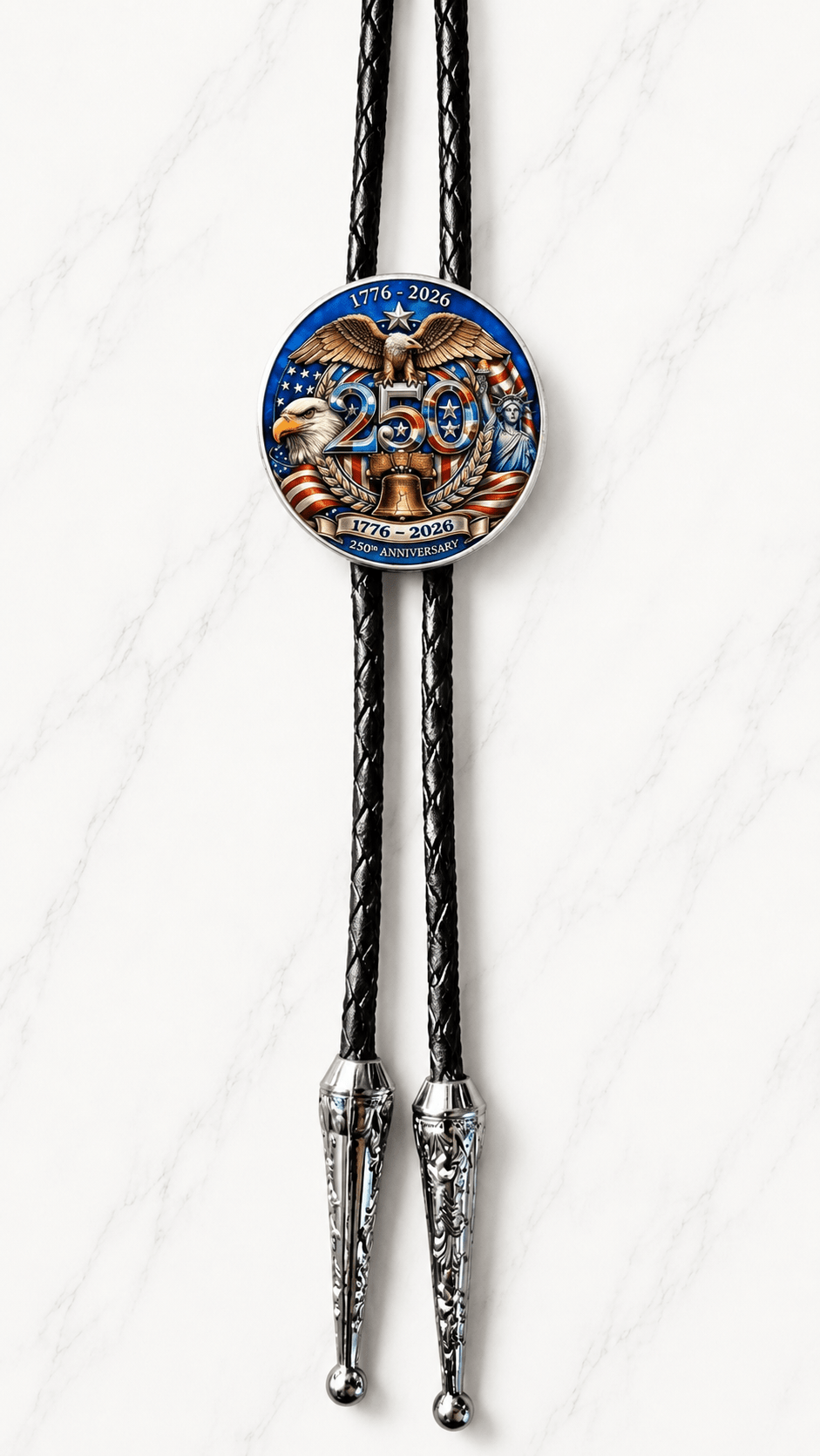 The Liberty Eagle Bolo Tie Side A featuring an America 250 commemorative centerpiece with bald eagles, Statue of Liberty, Liberty Bell, black braided leather, and ornate silver-tone tips on white marble