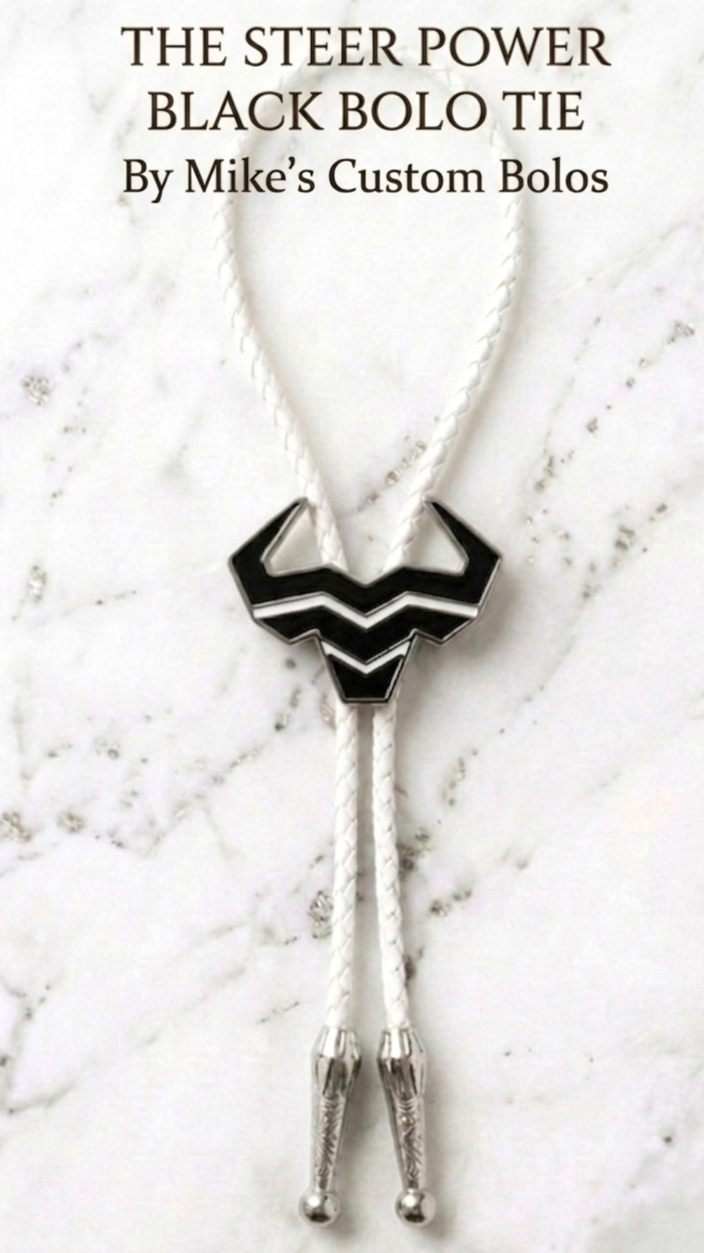 Black Steer Bolo Tie with white braided leather cord displayed on white with silver marble, handcrafted Western neckwear collaboration.