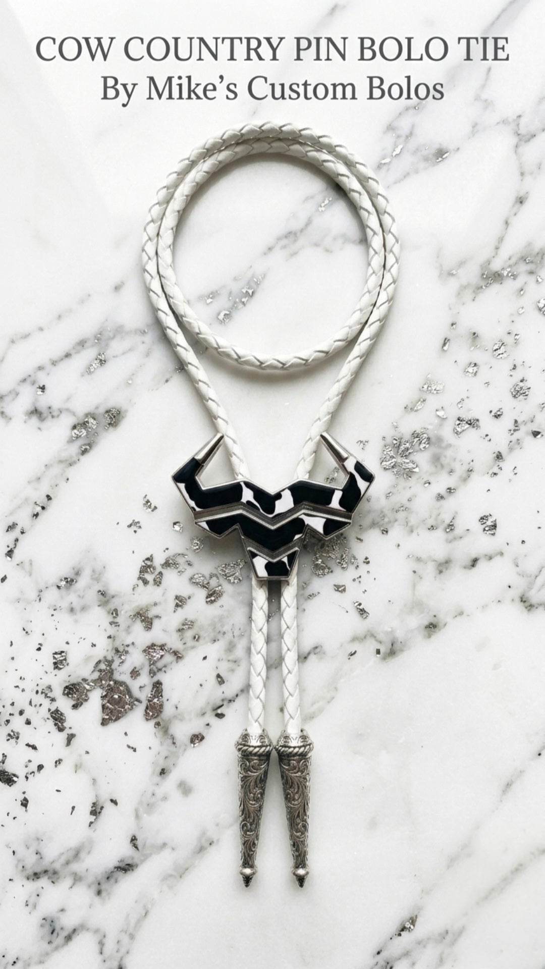 Cow country bolo tie on a white with silver marble surface with the text 'Cow Country Bolo Tie By Mike's Custom Bolos.'